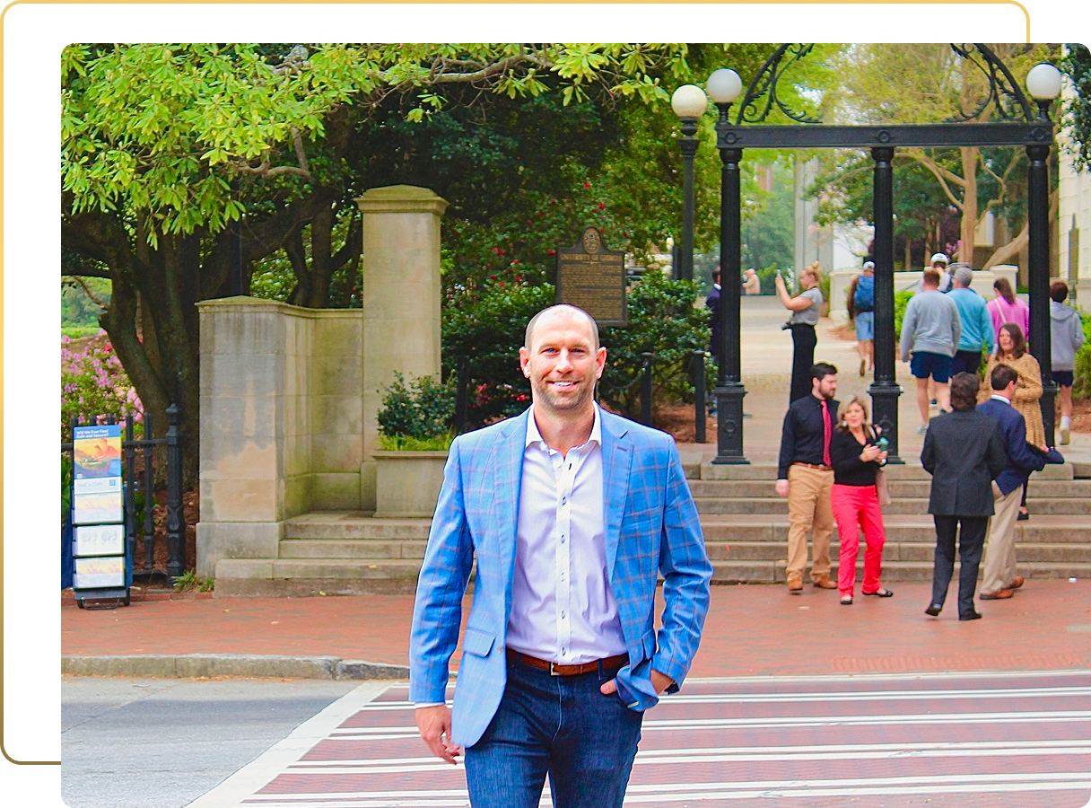 Smiling man in blue blazer standing on Athens street near historic columns and lamp posts