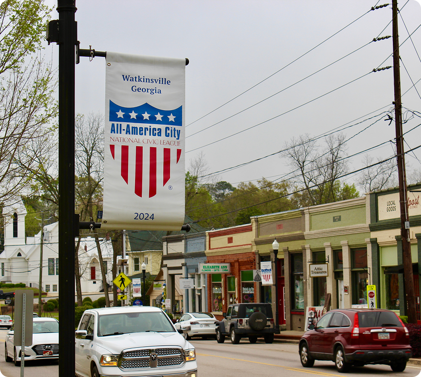 Watkinsville, Georgia All-America City 2024 banner on street with cars and shops